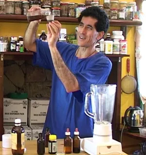 Dipaunka in the dispensary, shelves of tinctures behind him